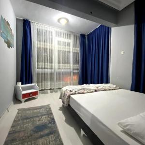 a bedroom with a bed and a window with blue curtains at Red White House in Antalya