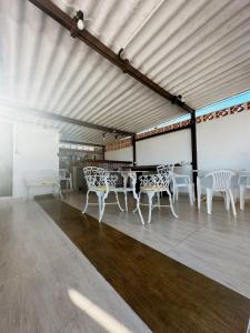 un grupo de mesas y sillas blancas bajo un techo en Casa com Churrasqueira próx a Praia das Astúrias, en Guarujá