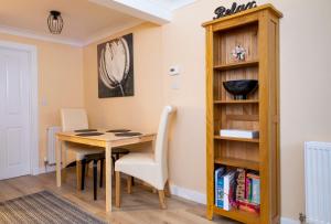 een eetkamer met een tafel en een boekenplank bij The Apartment at No.12 in Lochwinnoch