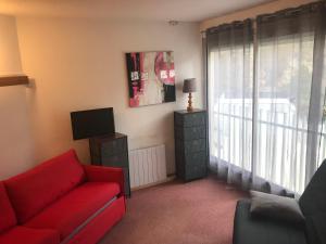 ein Wohnzimmer mit einem roten Sofa und einem TV in der Unterkunft STUDIO BAREGES- 1 pièce 4 personnes, Station ski BAREGES-LA MONGIE in Barèges