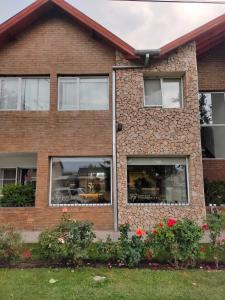 una casa de ladrillo con ventanas y flores en el patio en Hotel Sur Sur Patagónico en Esquel