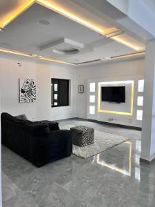 a living room with a black couch and a flat screen tv at Villa Serenity with Swimming Pool, Home Theater, and Gym in Baguida