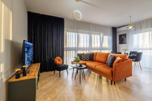 a living room with an orange couch and a table at Emihouse Riverside Apartments in Rzeszów