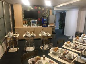 a restaurant with tables and chairs and a flat screen tv at Hôtel Le Cousture in Toulouse