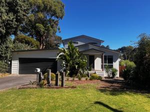 a white house with a garage in a yard at Bay Breeze Retreat in Cowes