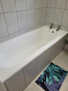 a white bath tub in a bathroom with a rug at TRASHAVEN - Seaside Haven Backpackers in Durban