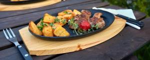 talerz jedzenia na drewnianej desce z mięsem i sałatką w obiekcie Dworek Tucholski w mieście Zblewo