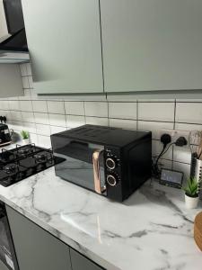 a black microwave sitting on a counter in a kitchen at 4 Bedroom Entire Flat, Kings Cross Road in London