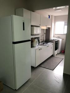 a kitchen with white cabinets and a refrigerator at Apto 70m² no centro de Porto Belo in Porto Belo