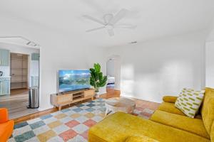 a living room with a yellow couch and a flat screen tv at Fire Pit + Grill + 2MI to DT Orlando in Orlando