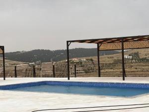 a swimming pool with a gazebo in front of a hill at Northern View in Kafr Khall