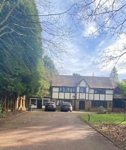 a large house with two cars parked in the driveway at Modern studio in natural surroundings in Four Oaks