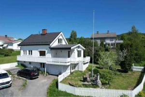 a white house with a car parked in front of it at Solrikt og sentralt. Ta med både to og firbeinte in Lillehammer