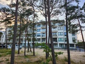 an apartment building with trees in front of it at Apartament, Wypoczynkowa Rowy in Rowy