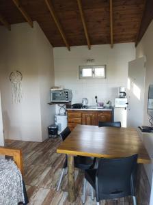 a kitchen and dining room with a wooden table and chairs at Cabañas La Retama in Tandil