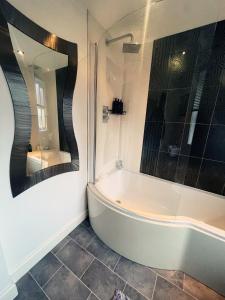 a bathroom with a bath tub and a mirror at Willow’s Abode: Luxury One Bed in Newton in Makerfield