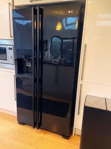 una nevera negra en una cocina con la puerta abierta en Willow’s Abode: Luxury One Bed, en Newton in Makerfield