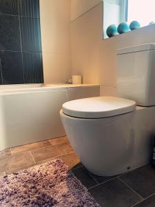 a bathroom with a toilet and a tub and a rug at Willow’s Abode: Luxury One Bed in Newton in Makerfield