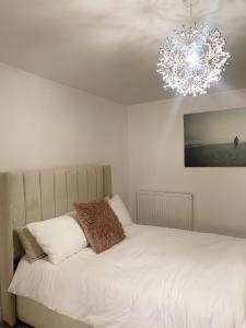 a bedroom with a white bed and a chandelier at Willow’s Abode: Luxury One Bed in Newton in Makerfield