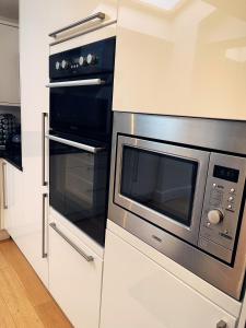 una cocina con microondas de acero inoxidable y horno en Willow’s Abode: Luxury One Bed, en Newton in Makerfield