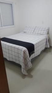 un letto in una camera bianca con una coperta sopra di Casa sobrado 7 a Guarujá