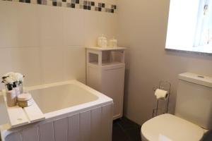 a bathroom with a white tub and a toilet at Cosy thatched Cottage sleeps 6 near Portscatho! in Porthscatho