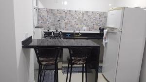 eine Küche mit schwarzer Theke und Kühlschrank in der Unterkunft CASA SETE ENSEADA AR COND Suíte E ESTACIONAMENTO GRÁTIS e uma ótima localização na enseada in Guarujá