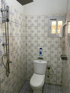 a bathroom with a toilet and blue and white tiles at Cave Royale - Chambres-Studios-Apparts meublés - Logpom Hopithal des soeurs ápres Camara Laye in Douala