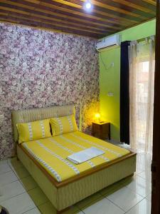 Bett in einem Zimmer mit einer Wand in der Unterkunft Cave Royale - Chambres-Studios-Apparts meublés - Logpom Hopithal des soeurs ápres Camara Laye in Douala
