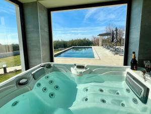 a bath tub with a view of a swimming pool at Villa Maslinik in Kaštelir