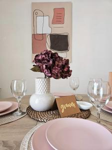 uma mesa com um prato e um vaso com flores roxas em CASA BLANCA em Santa Pola