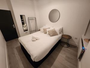 1 dormitorio con cama blanca y espejo redondo en SuperValue Suite 6 - Fast WiFi, Hotel Linen, Keyless Entry, City only 10 Mins - BY PROPERTY PROMISE, en Cardiff