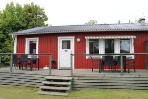 a red house with a table and chairs on a deck at Sandby Pensionat in Löttorp