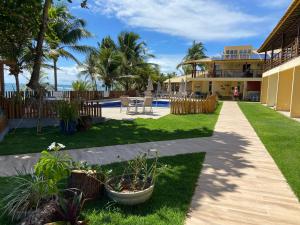 a house with a yard with a table and chairs at Vilage beira-mar Itacimirim in Camaçari