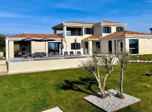 a house with a yard with two trees at Villa Maslinik in Kaštelir