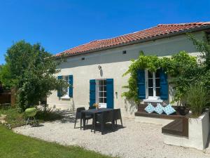 Casa blanca con mesa negra y persianas azules en Le Moulin du Clapier La Banette en Sorges
