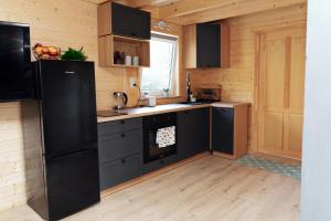 a kitchen with black appliances and wooden walls at Domek letniskowy Letniczówka in Warchały