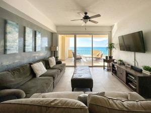 a living room with a couch and a flat screen tv at Family friendly Condo with Oceanfront Views in Puerto Peñasco