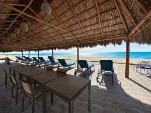a row of tables and chairs on the beach at Family friendly Condo with Oceanfront Views in Puerto Peñasco