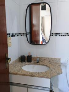 a bathroom with a sink and a mirror at Triplex 3 quartos a 100 metros de Costa Azul in Rio das Ostras
