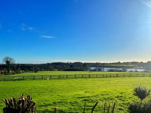 um grande campo verde com uma cerca ao fundo em The Starlings Country House em Wexford
