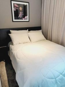 1 cama con sábanas blancas y almohadas en una habitación en Apto completo perto Hosp Sirio Libanês, en São Paulo