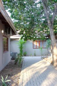 a tree in front of a house with a sidewalk at Delta Sunset View in Maun