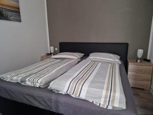 a bed with a striped blanket and pillows on it at Ferienwohnung Baltrum auf dem Elisenhof Hagermarsch in Hagermarsch