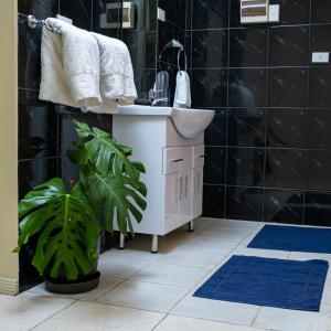 baño con lavabo blanco y alfombra azul en Croton House, Nadi, en Nadi