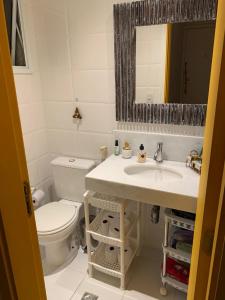 a bathroom with a toilet and a sink and a mirror at apartamento barra da tijuca in Rio de Janeiro