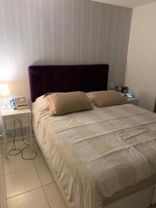 a bedroom with a large bed with a purple headboard at apartamento barra da tijuca in Rio de Janeiro