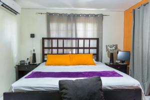 a bedroom with a bed with an orange and purple pillow at The Biltons - 6 min from airport- A/C in all rooms in Montego Bay