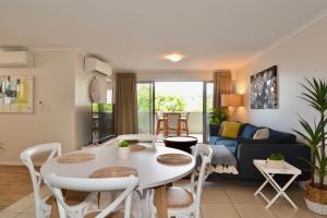 sala de estar con mesa blanca y sillas en City Stadium Apartment on the riverfront en Townsville