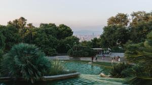 des personnes se promenant autour d'un étang dans un parc dans l'établissement Hotel Indigo Barcelona Plaza Espana, an IHG Hotel, à Barcelone